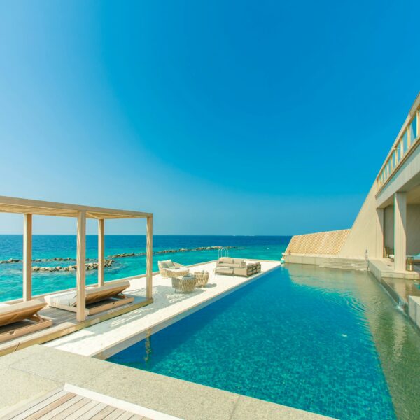 Stunning view of a luxury resort in Maldives with an infinity pool overlooking the ocean.