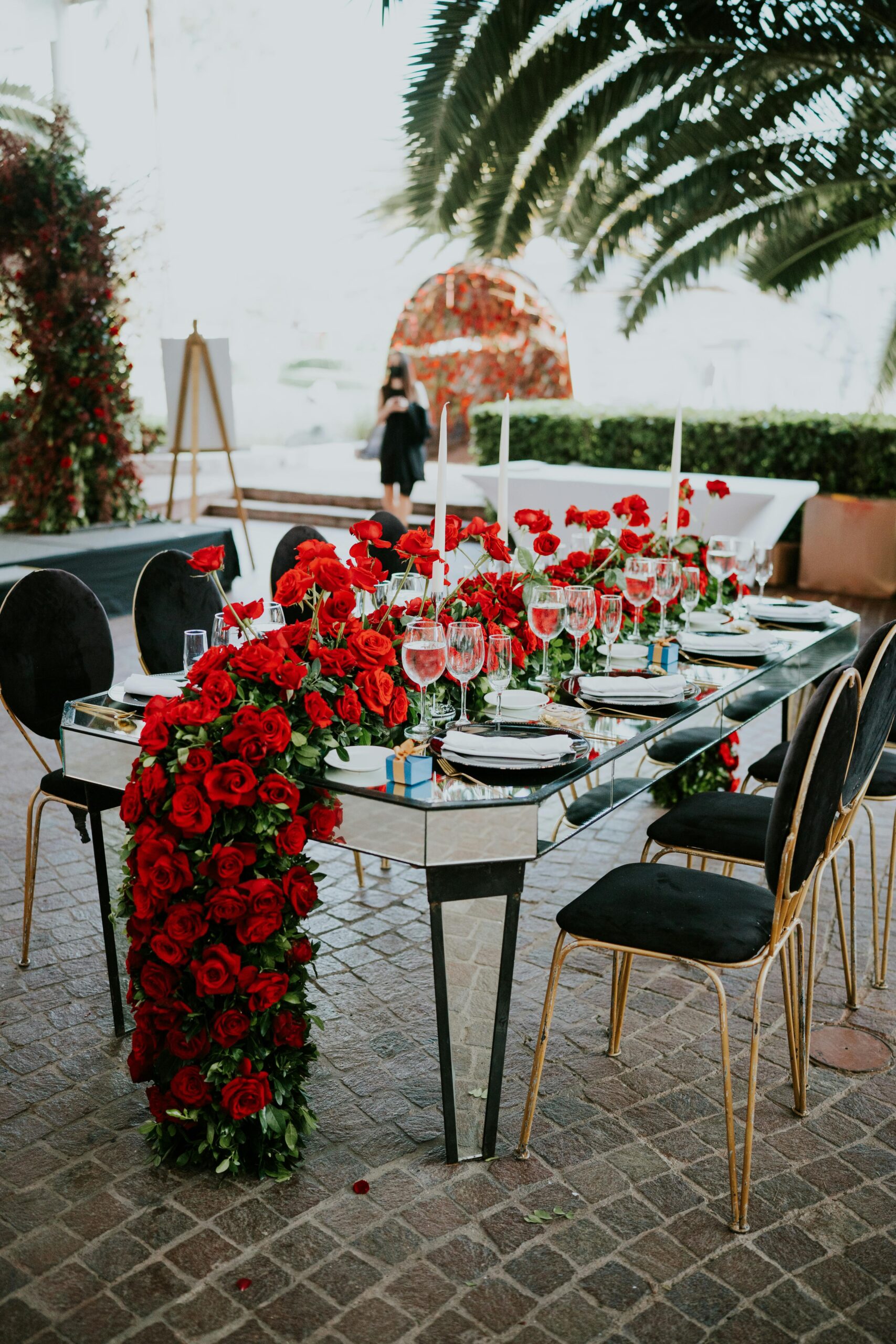 Outdoor dining setup with red roses and elegant tableware, perfect for romantic events.