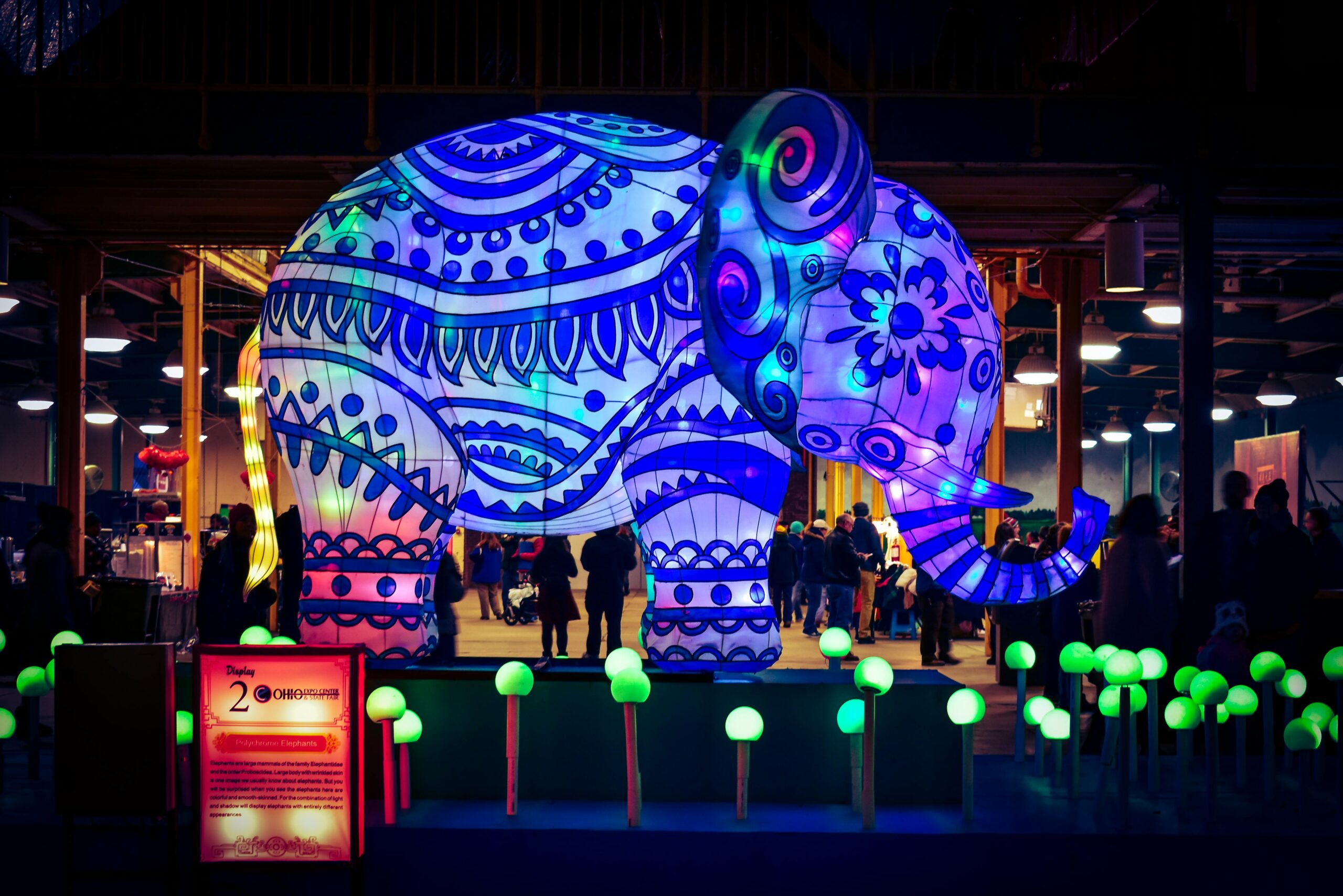 Colorful illuminated elephant lantern at an outdoor night festival, creating a lively atmosphere.
