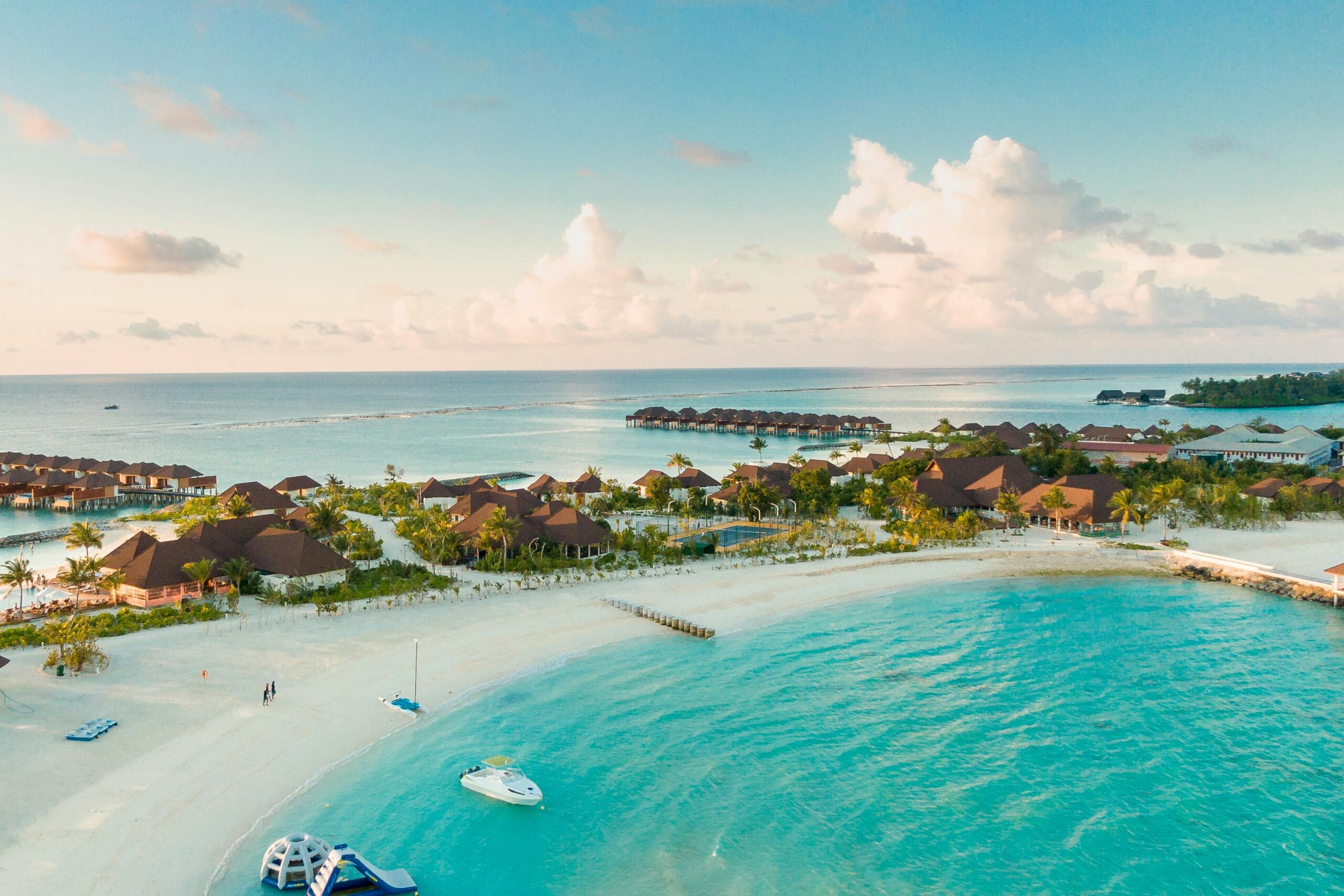 A stunning aerial view of a tropical Maldives beach with clear turquoise waters and resorts along the shore.